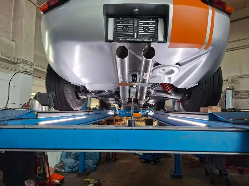 Polished stainless twin exhaust beneath the rebuilt rear suspension